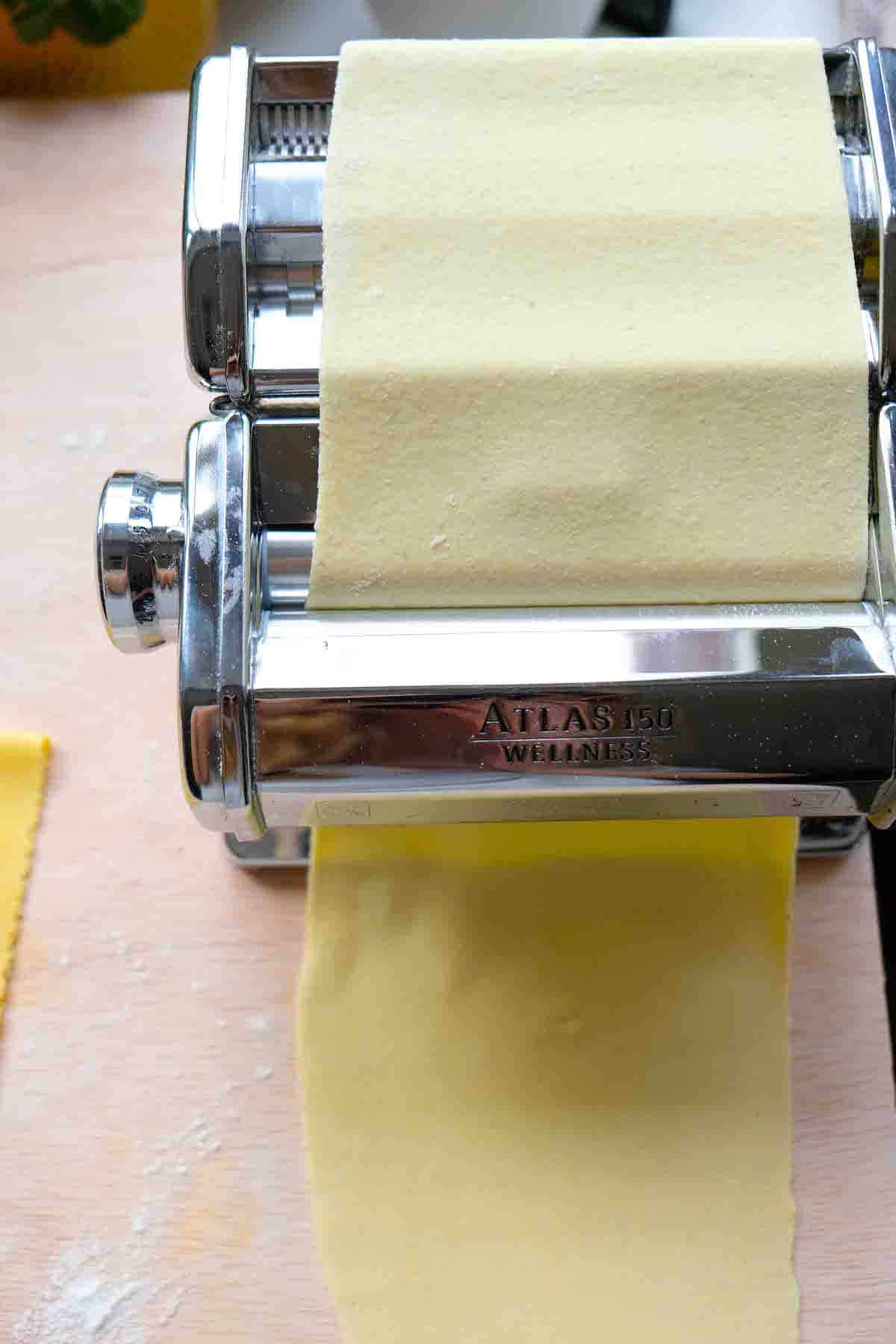 Rolling out semolina pasta dough using a manual hand crank Mercato Atlas pasta roller machine.