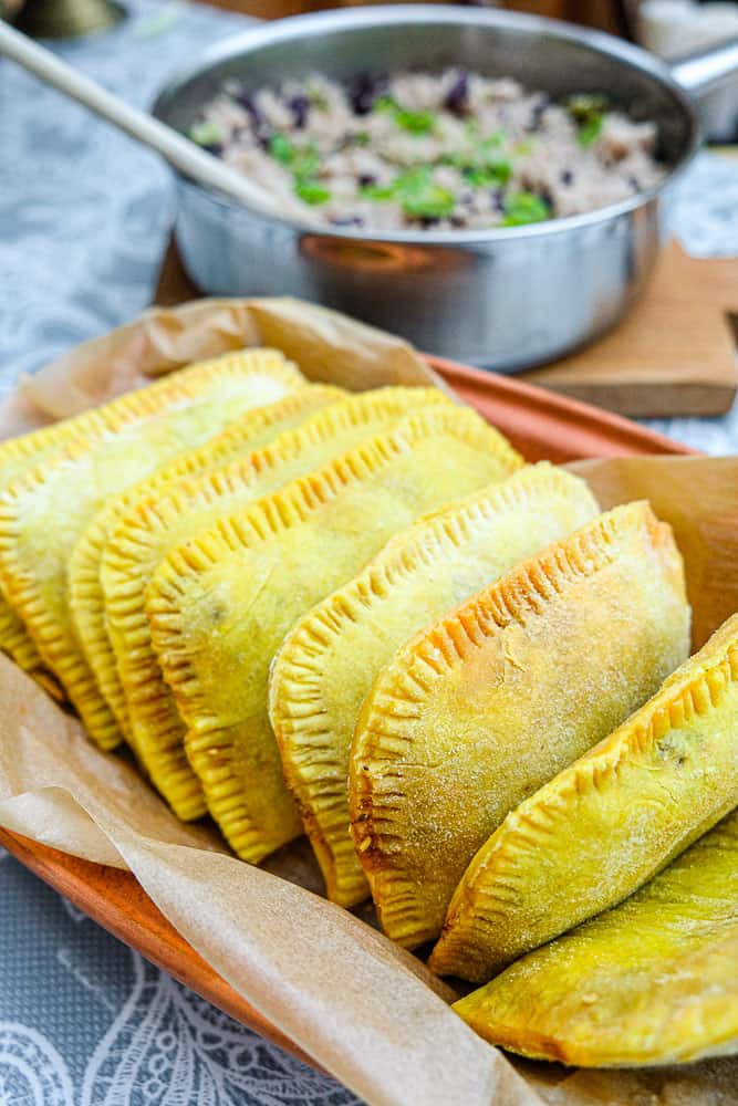 Homemade Jamaican beef patties with rice and peas in the background.
