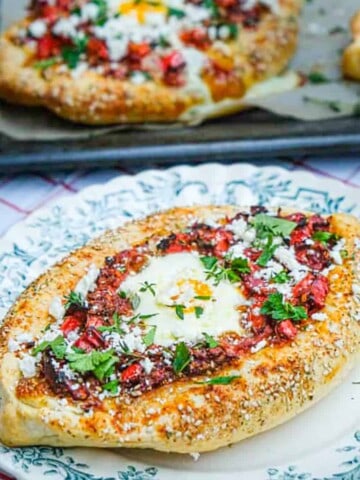 shakshuka stuffed inside khachapuri bread with an egg in the middle and sprinkled feta cheese crumbled on top.