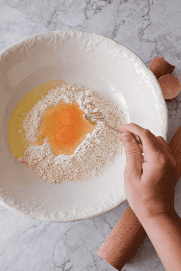 Mixing egg and flour pasta dough to make homemade pasta.