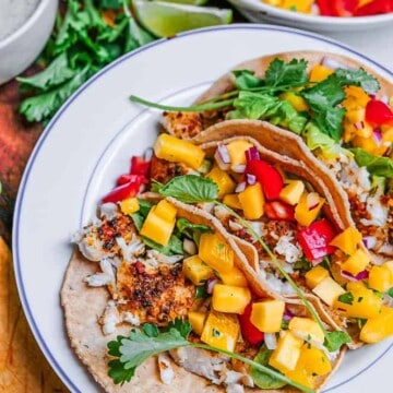 These fish tacos with mango salsa and creamy white lightning sauce are full of vibrant flavours layered together to create a perfect bite. Made with baked fish and lots of fresh ingredients, they’re healthy but they taste like pure indulgence. All for only 400 calories and 10 grams of fat per serving of 3. The best part is that they’re quick and easy to make. Fish tacos are the answer to boring weeknight meals.