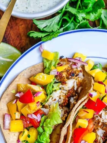 Three baked fish tacos with mango salsa and white lightning sauce.