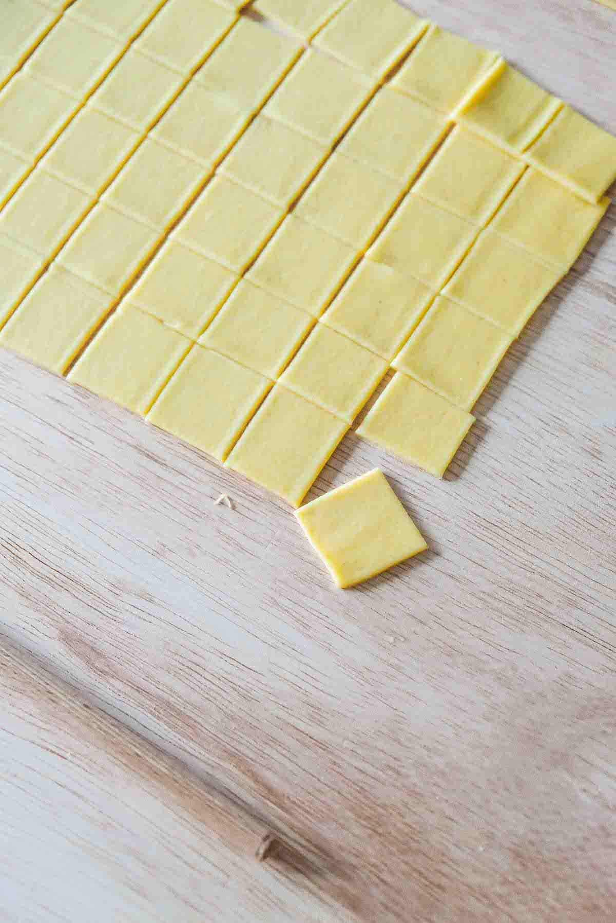 A sheet of semolina pasta dough cut into even squares.