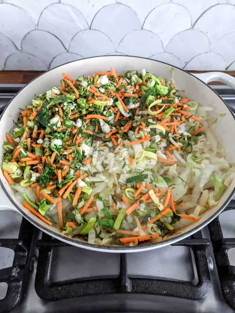 Finely diced vegetables and cabbage in a large pot before the water is added to turn it into soup.