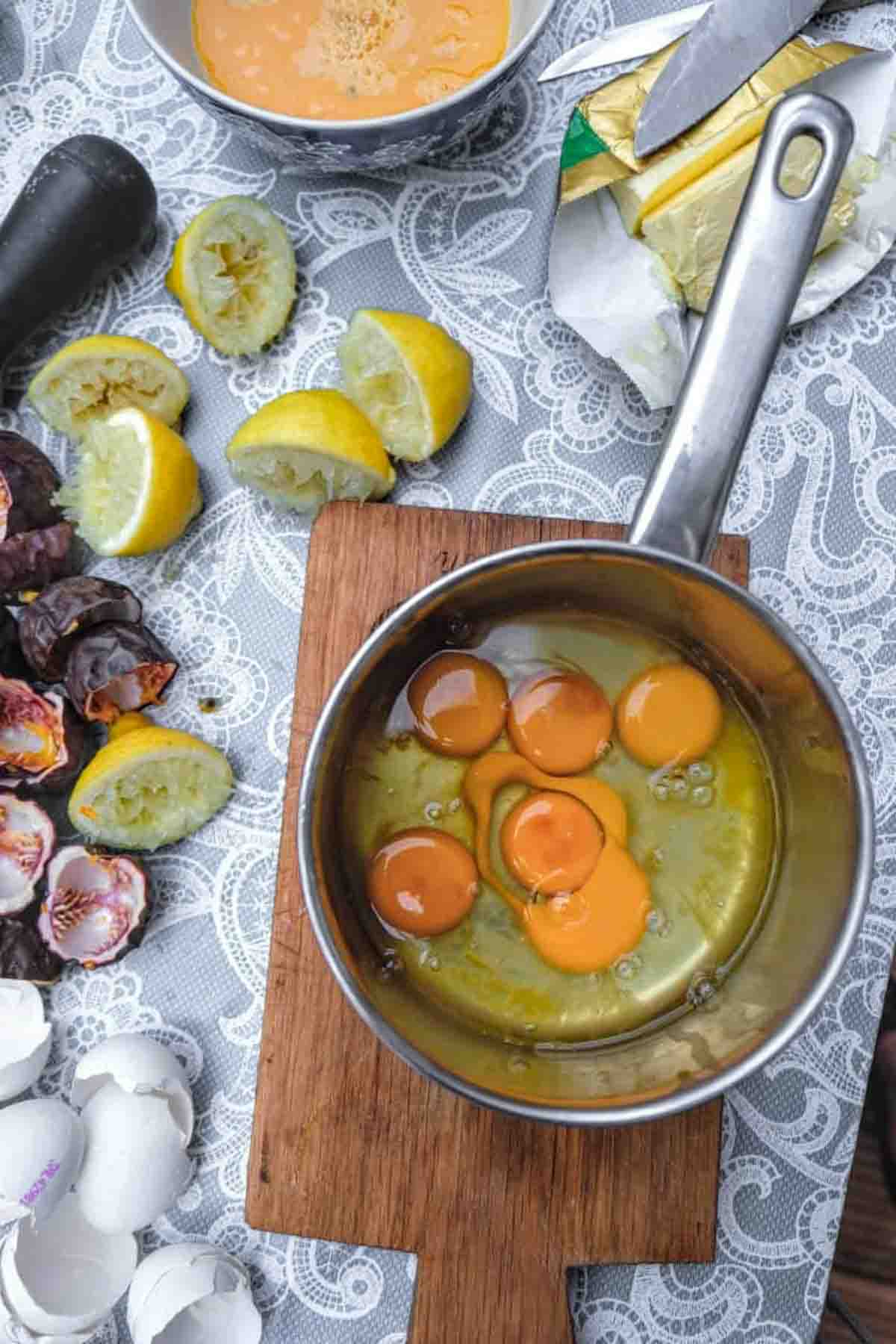 Whole eggs in a pot beside egg shells as well as lemon and passionfruit peels.