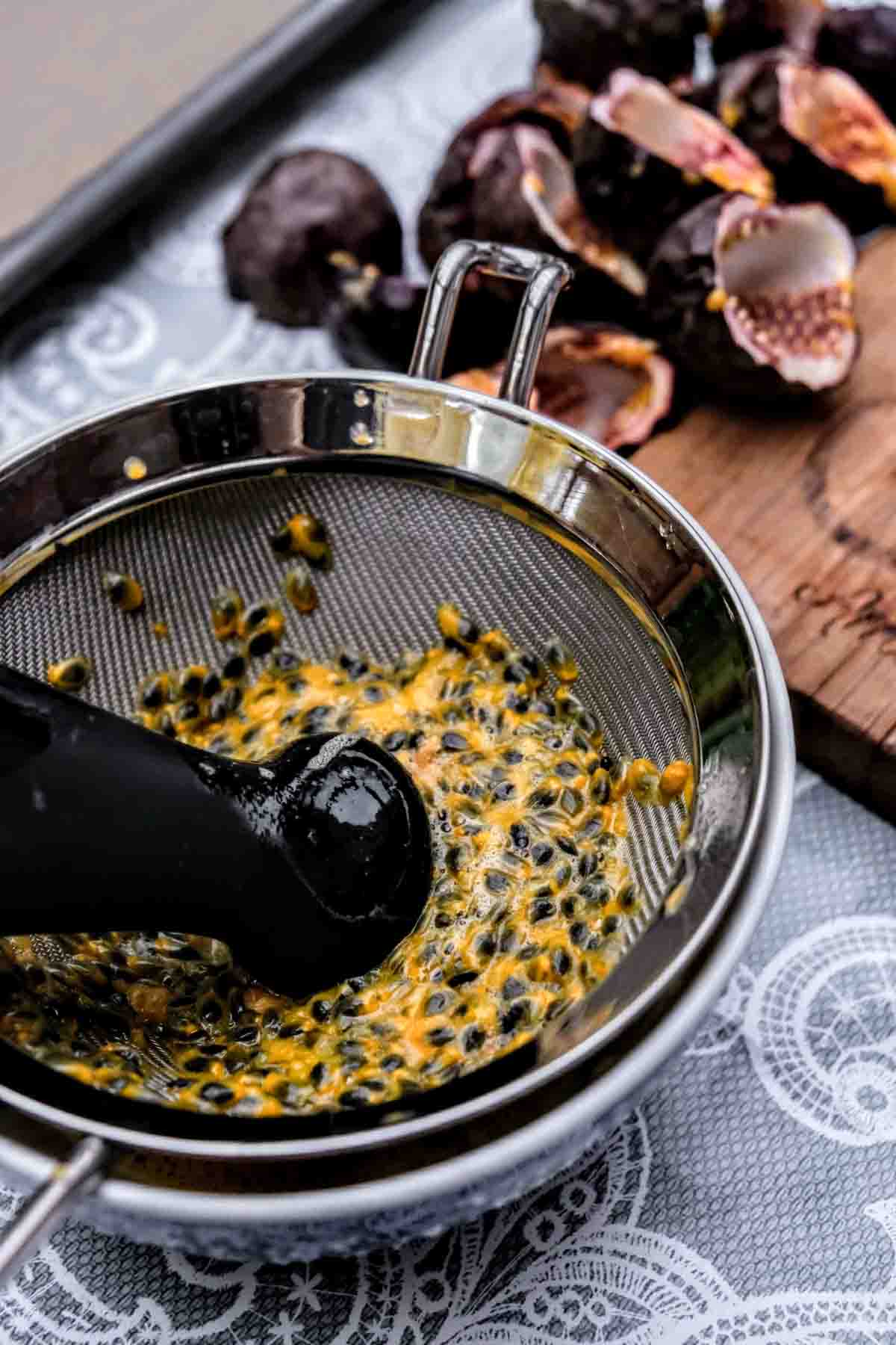Squeezing the juice out of passionfruit over a sieve. 