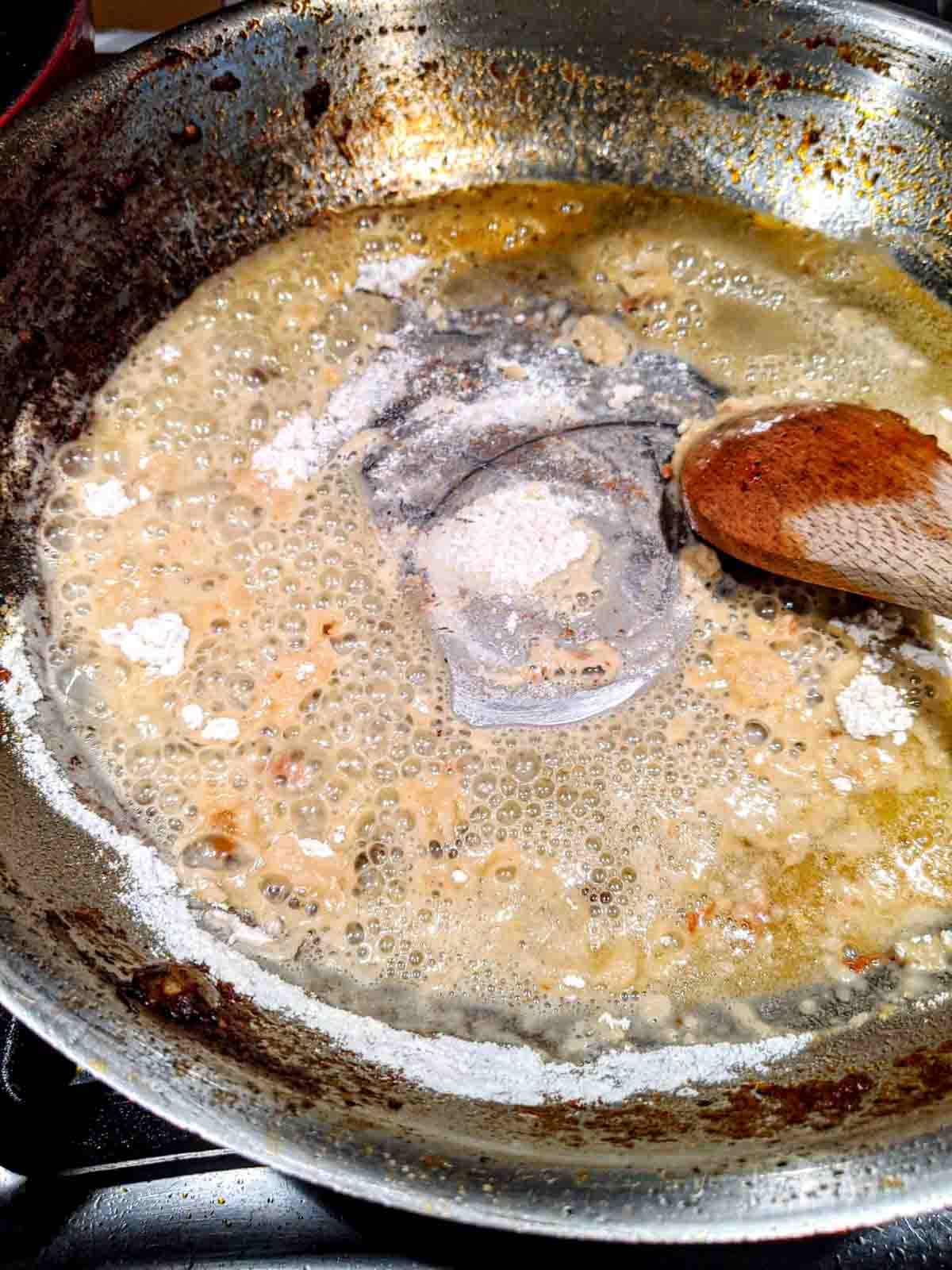 Mixing flour and butter in a skillet to make roux for the bechamel sauce.