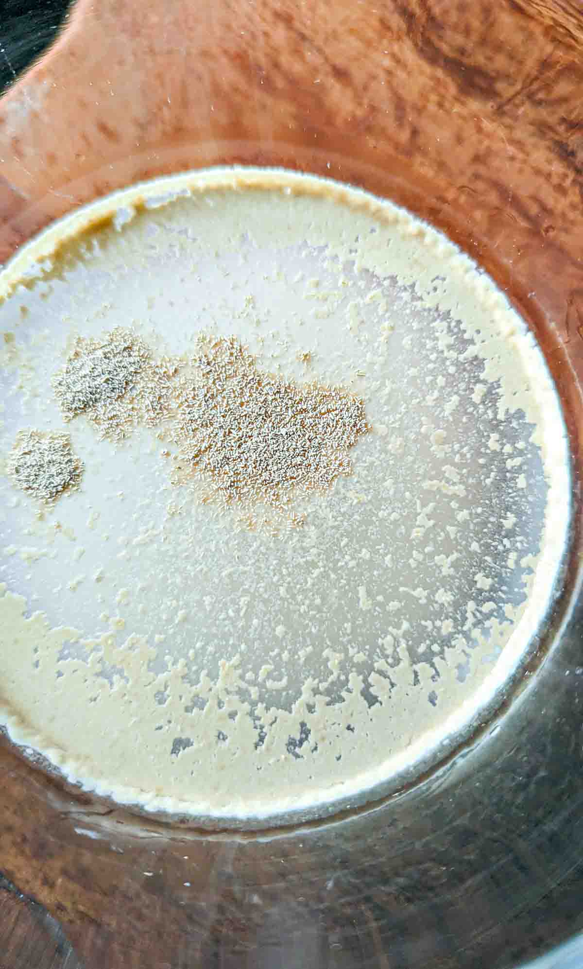 A glass of blooming yeast showing the foam forming along the edges.