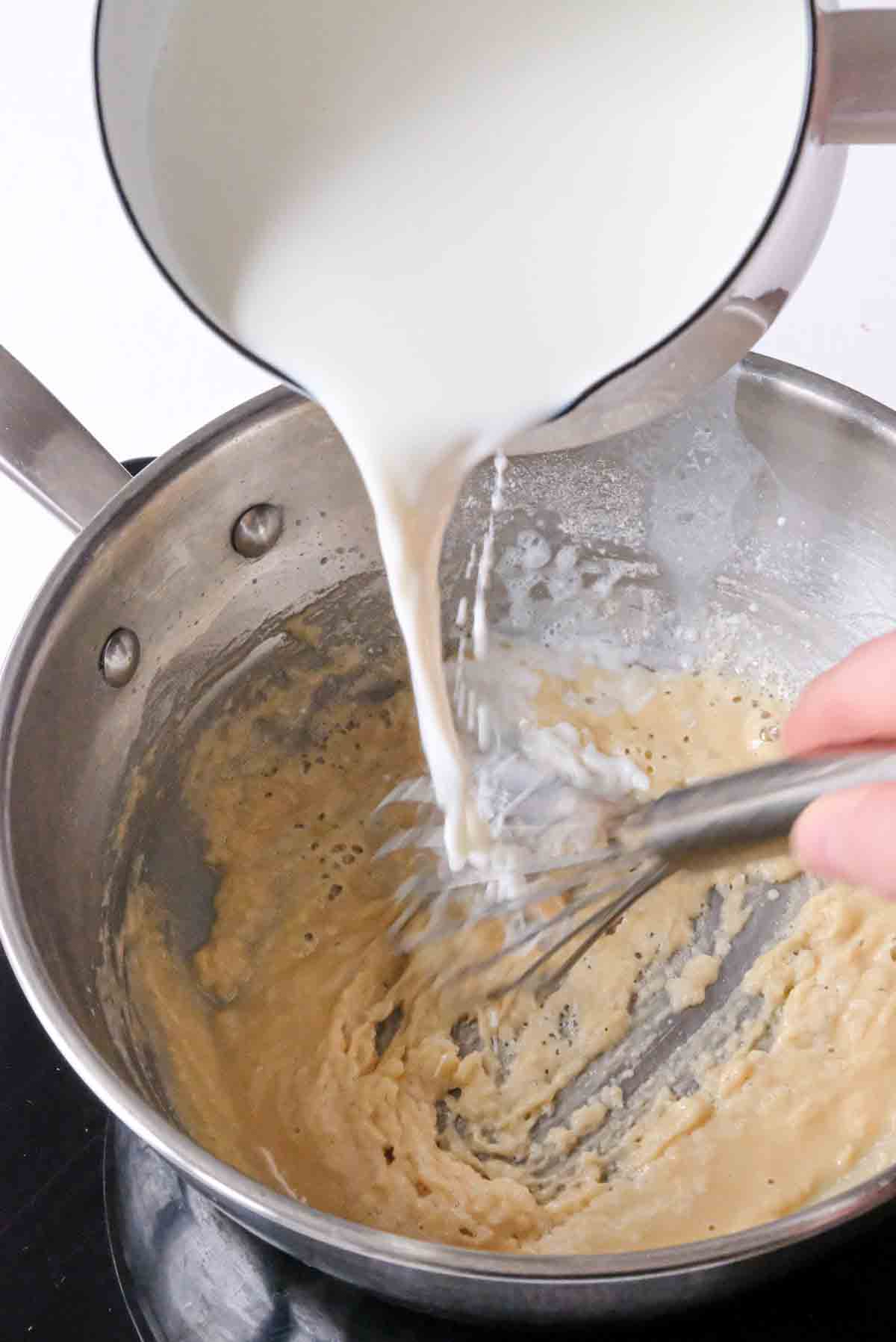 Pouring milk over a roux to make bechamel.