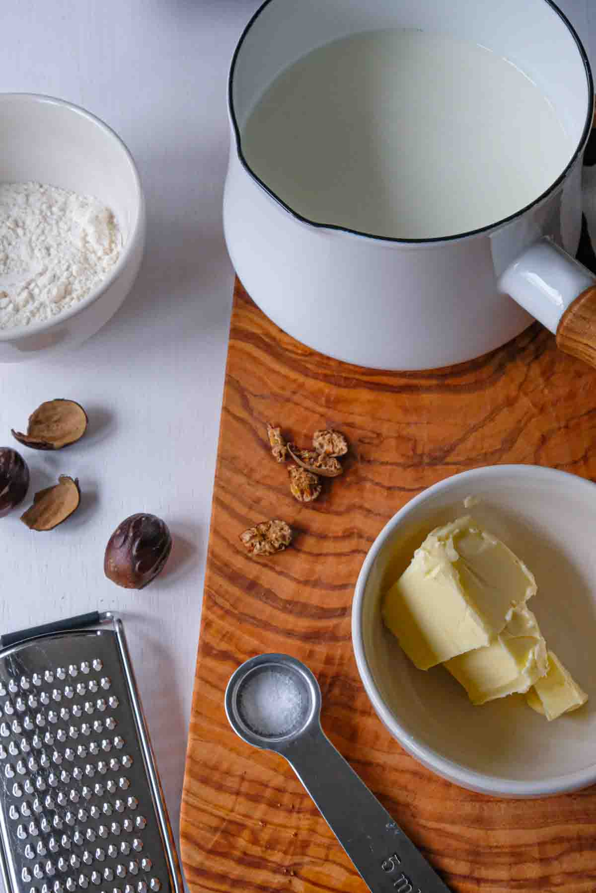 The ingredients to make bechamel including flour, butter, a small pot of milk, nutmeg and salt.