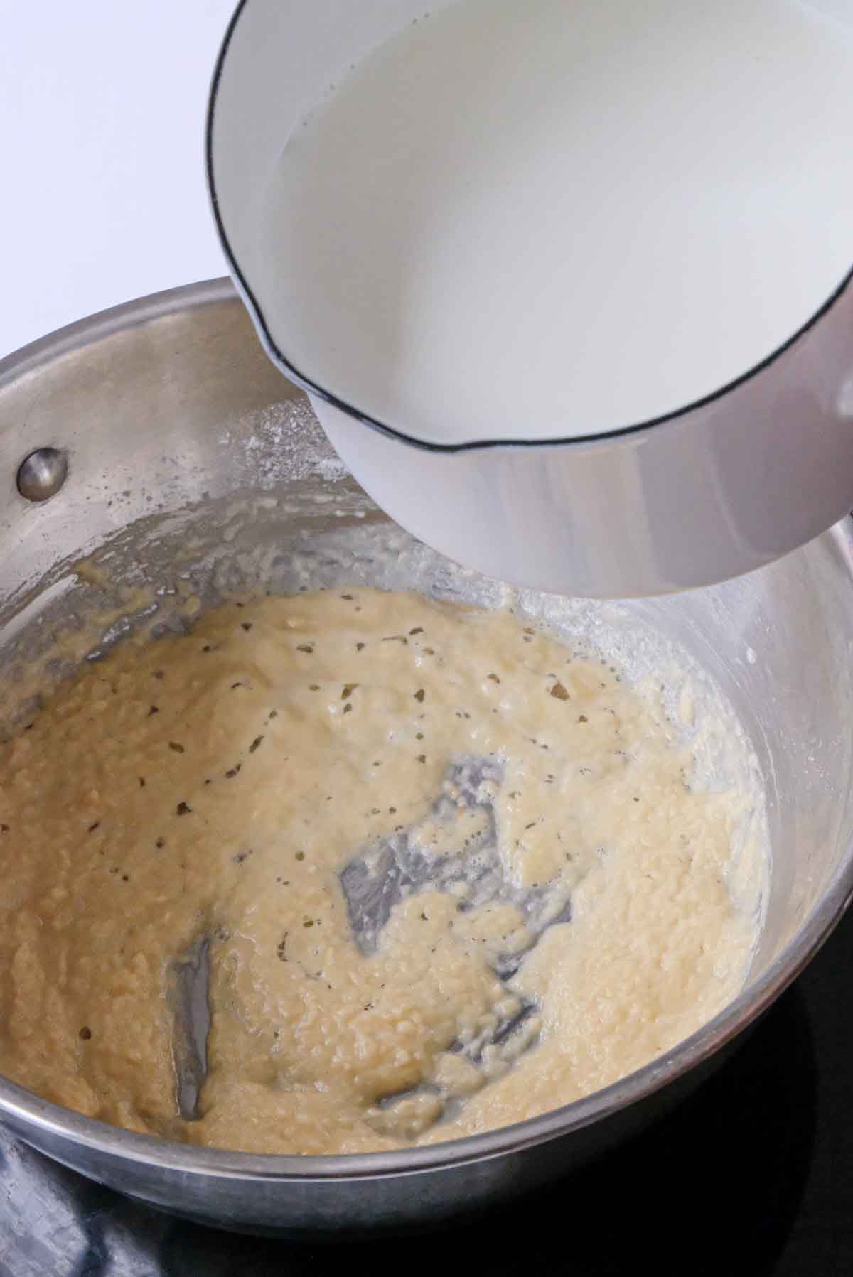 Pouring milk over a cooked mixture of butter and flour in order to make bechamel.