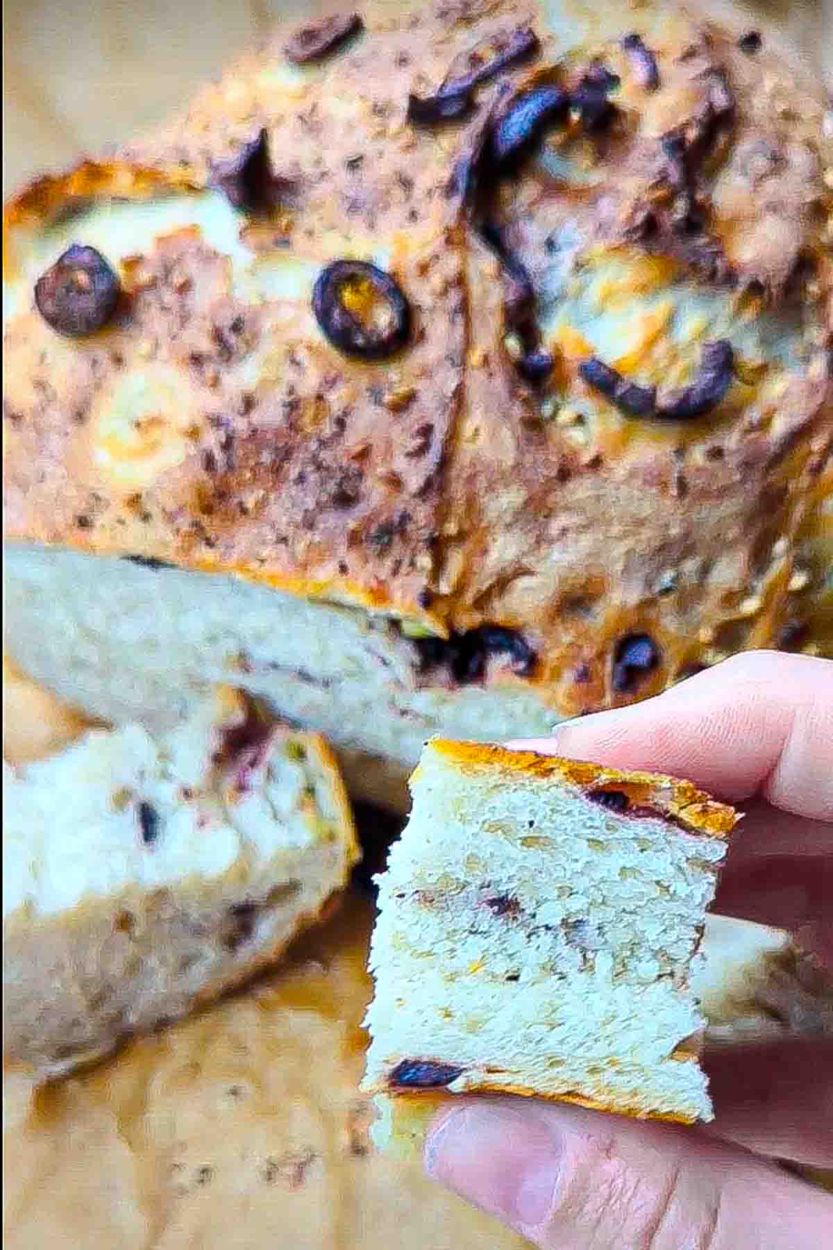 A slice of the sesame and olive bread being squeezed to show how much it compresses and how soft it is.