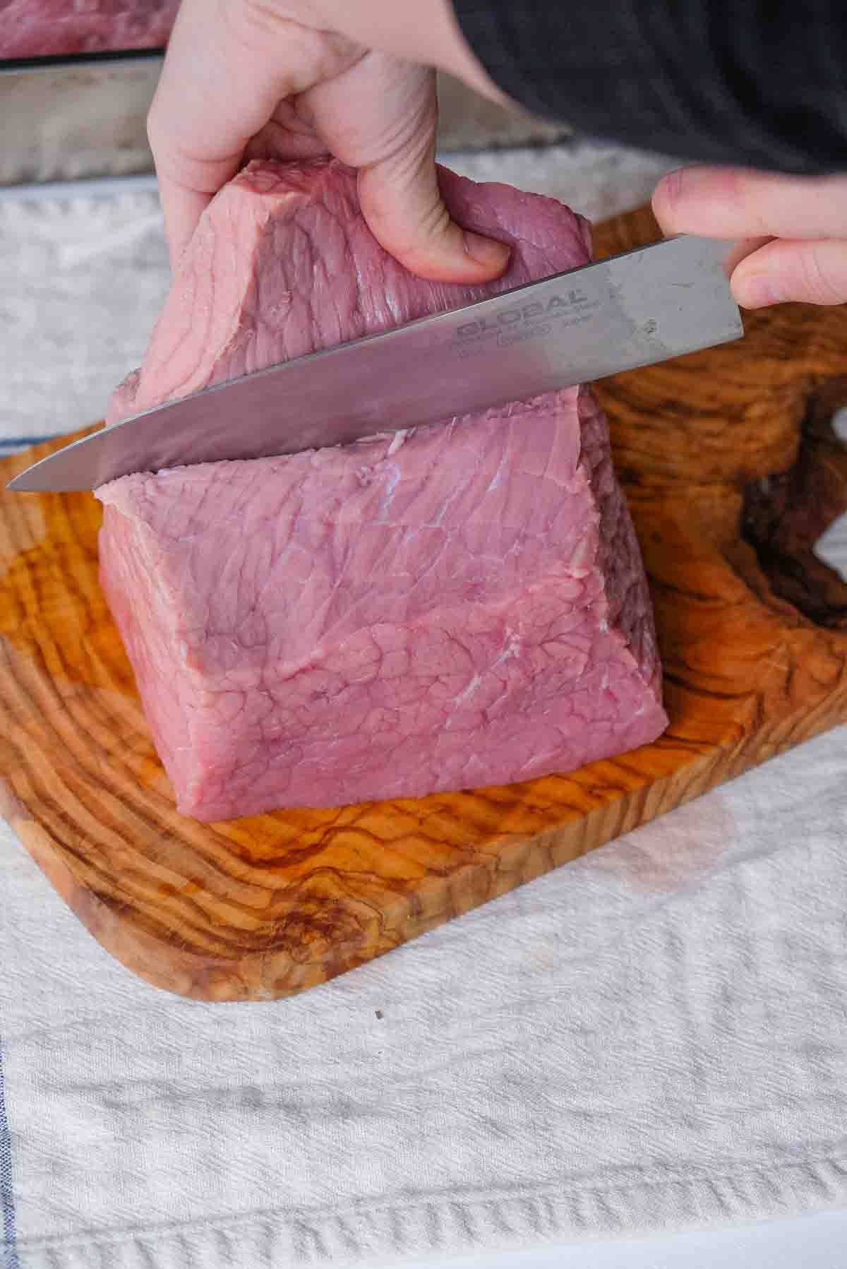 Cutting into a large veal rump in order to truss it.