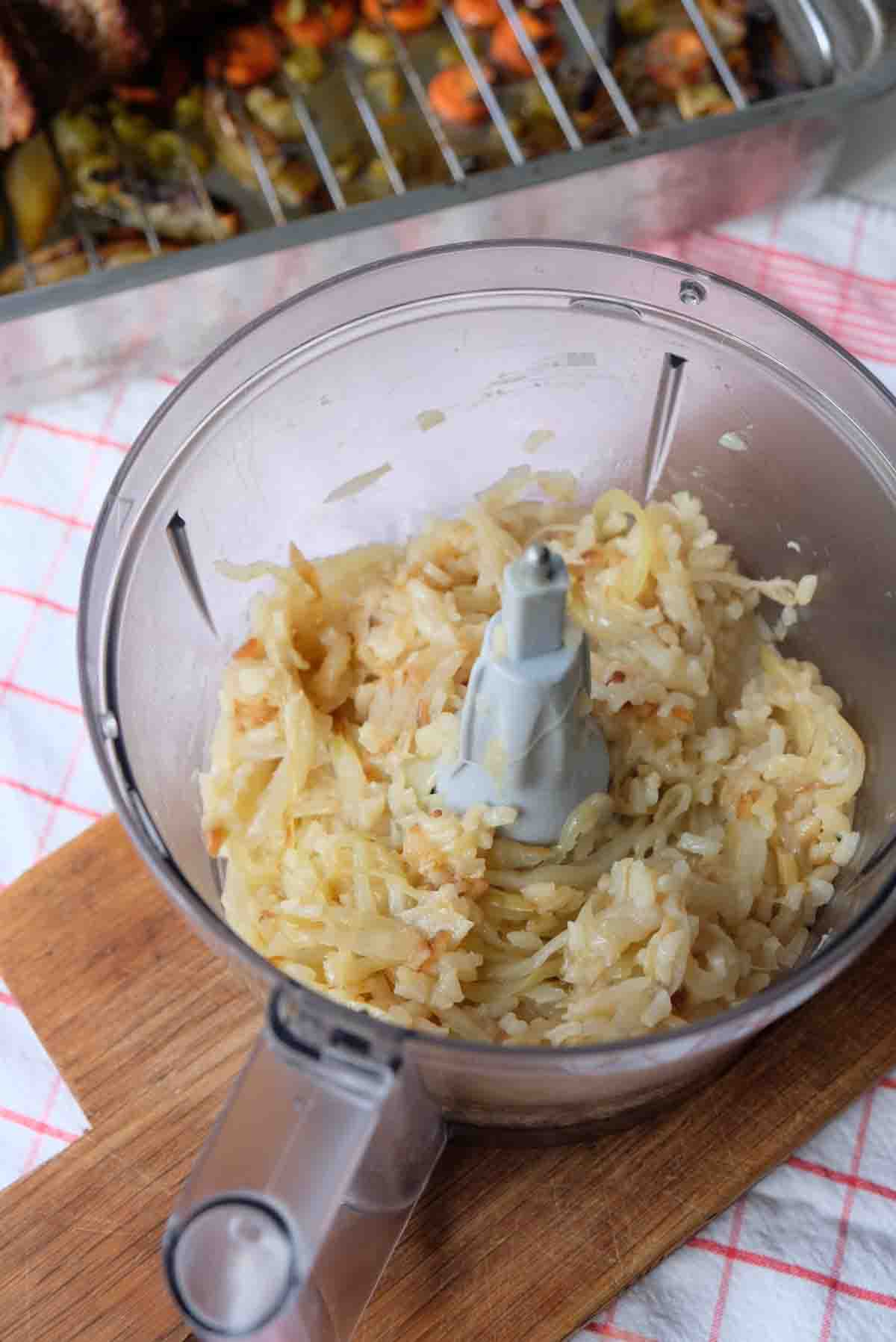 Onion and rice slow cooked in butter are in the bowl of a food processor ready to be blended into a smooth sauce. 