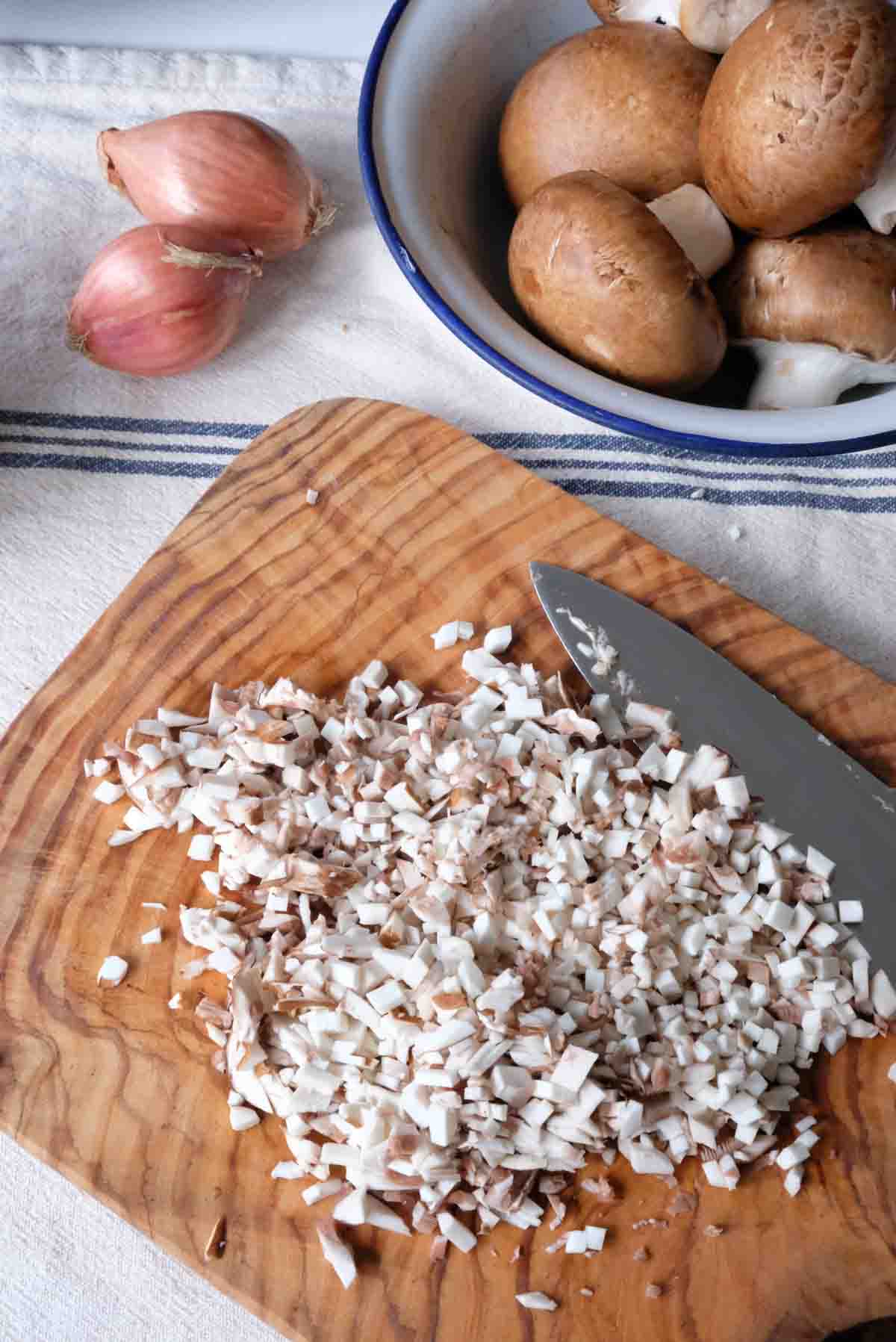 Mushrooms that have been finely diced with a knife. They are still individual pieces with defined edges.