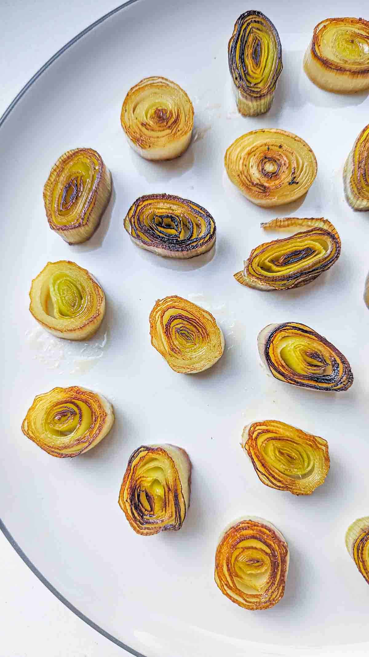 leek medallions roasted to a golden color laid out in a plate