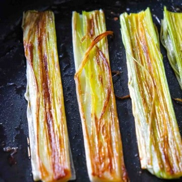 a caramelized leek cut lengthwise into 4 pieces and slow roasted in a cast iron skillet until golden