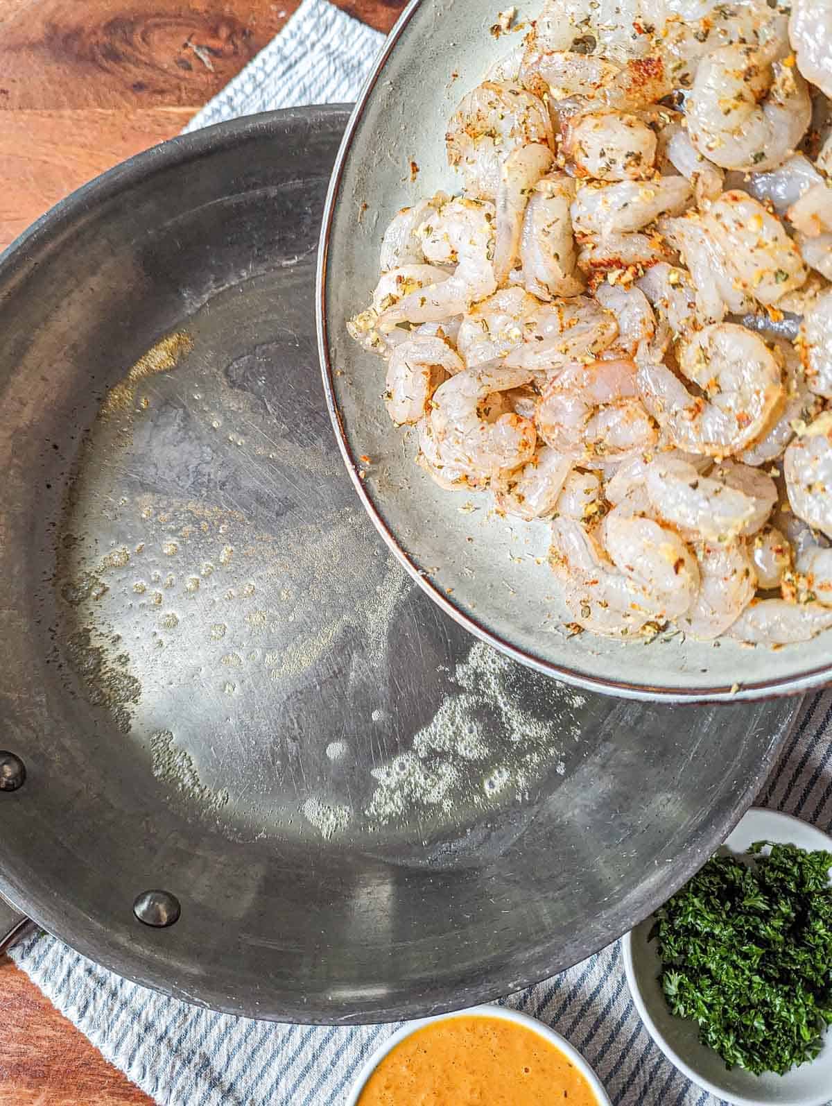 The seasoned shrimp being added to a pan with garlic butter.