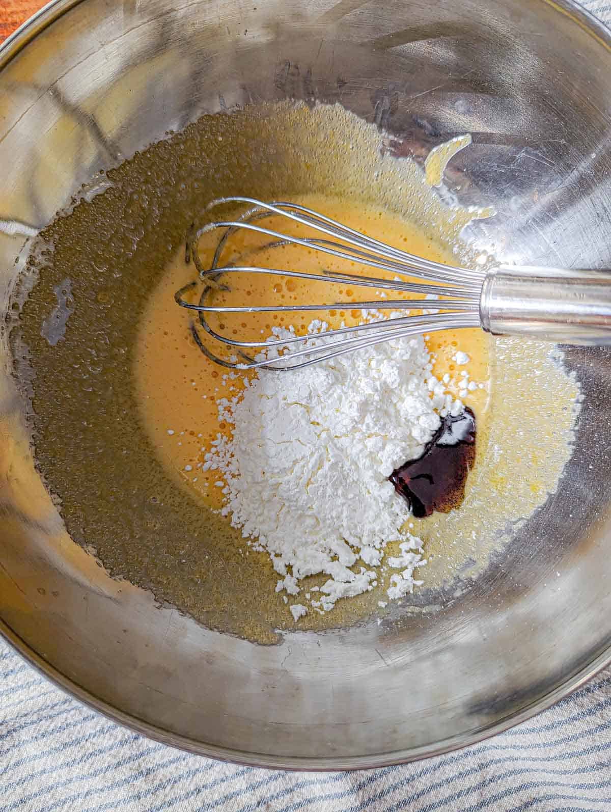 Combining cornstarch and vanilla into the beaten egg and sugar before adding hot milk to make pastry cream.