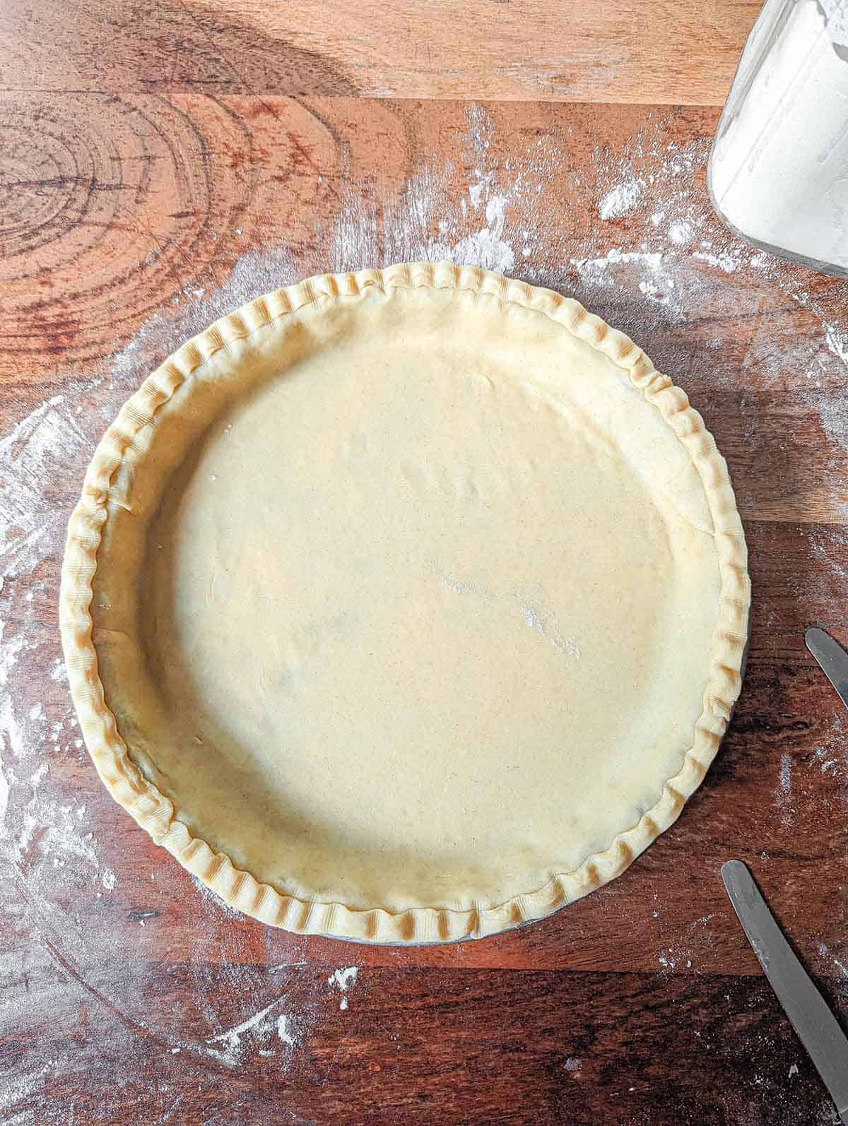 an overhead view of a tart pan with pie dough in it