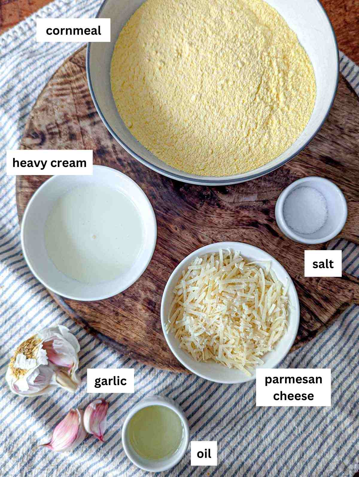 The ingredients for parmesan polenta including cornmeal, heavy cream, salt, parmesan cheese, garlic and olive oil.