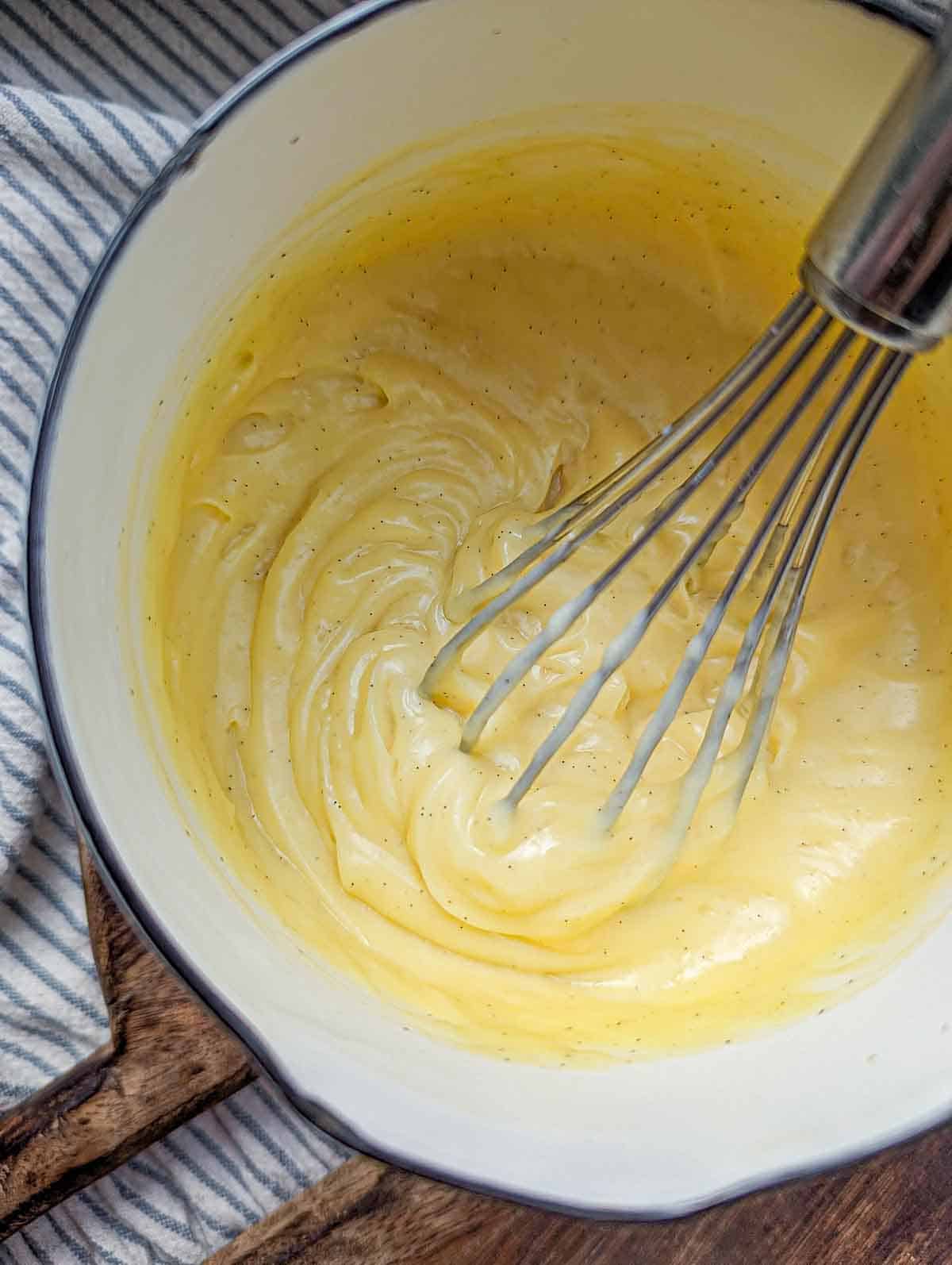 Whipping pastry cream in a pot with a whisk.