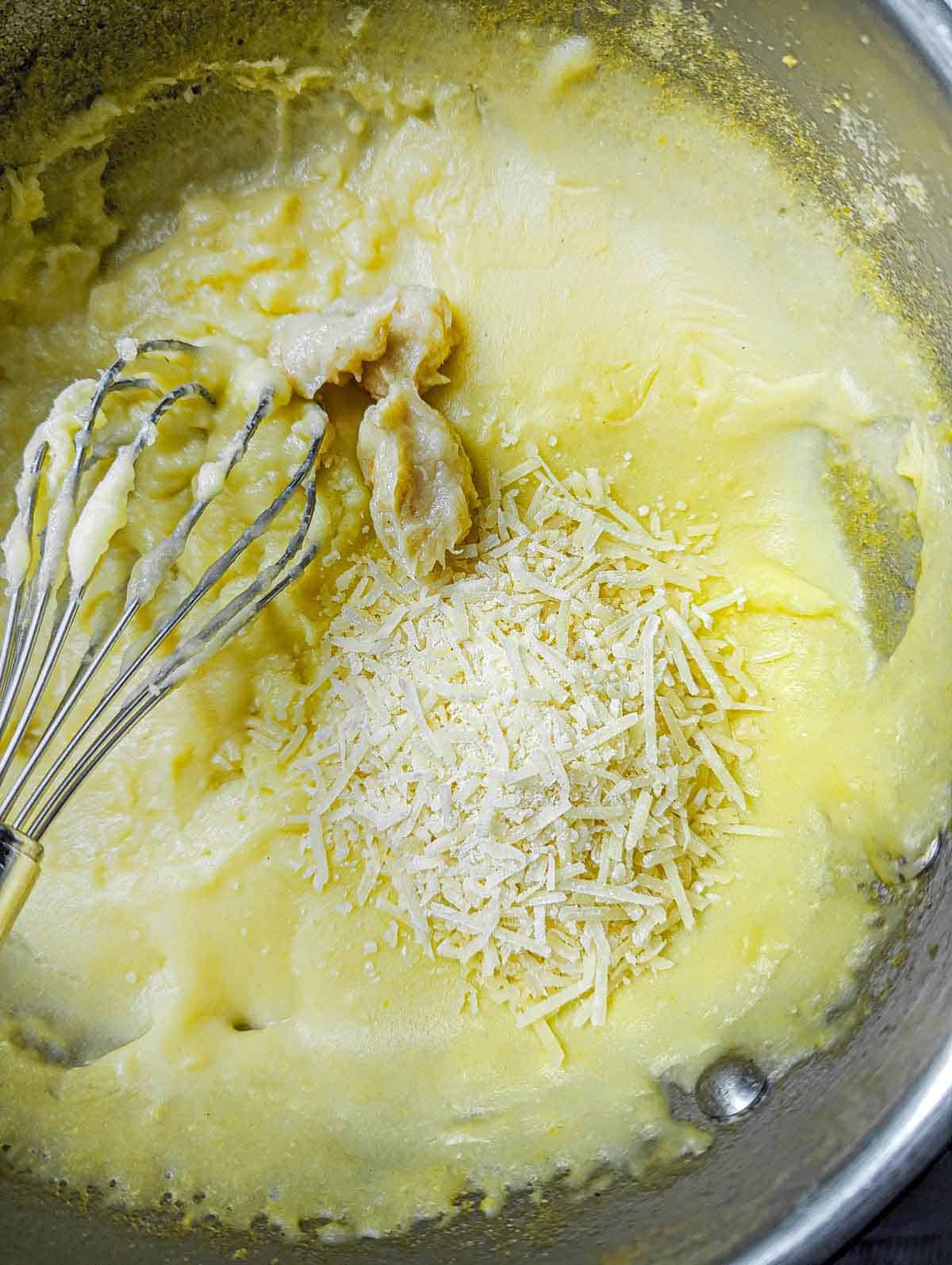 Whisking roasted garlic and parmesan into the cooked polenta.