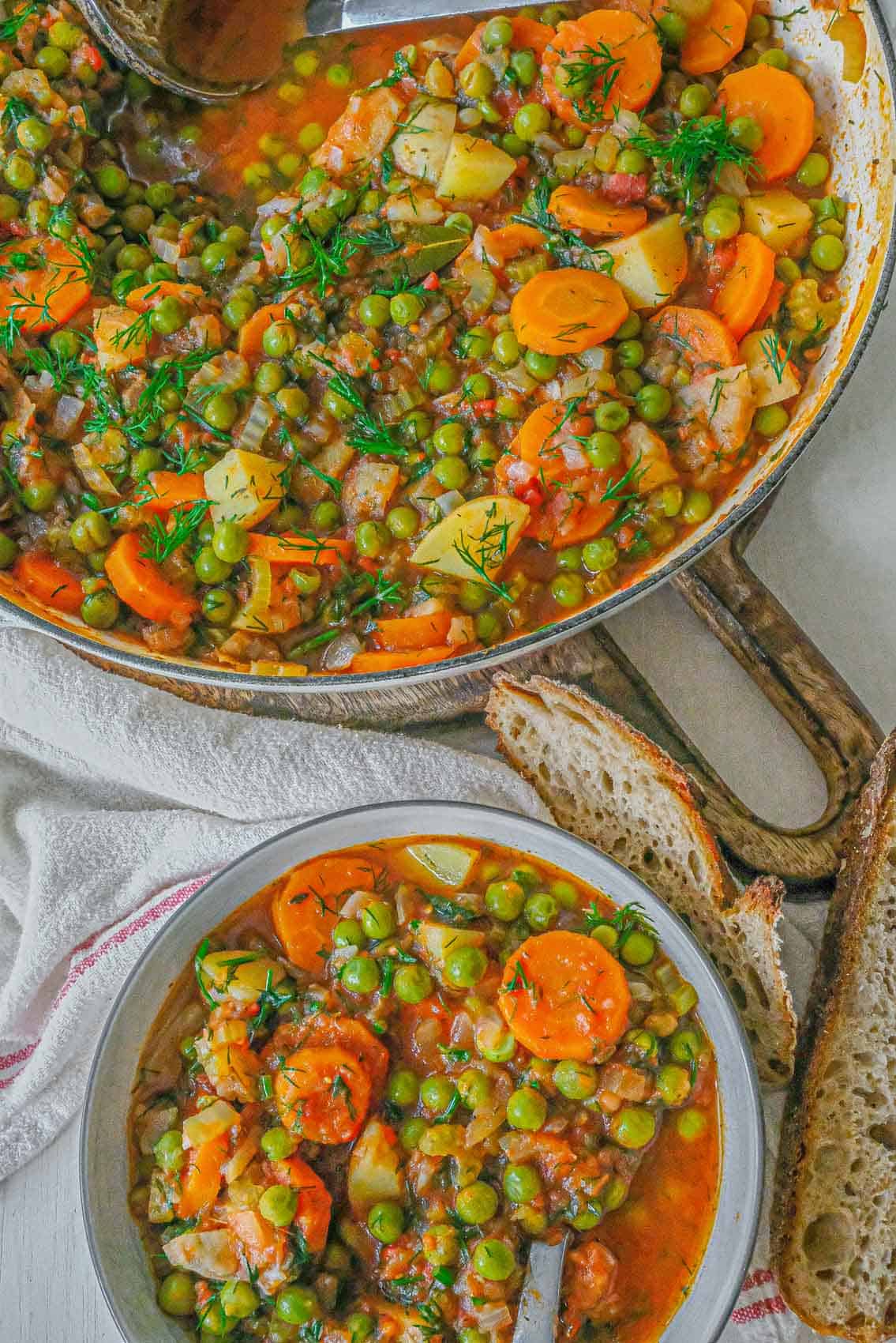 Romanian green pea stew served in a bowl with bread.