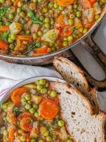 Romanian green pea stew served in a bowl with bread.