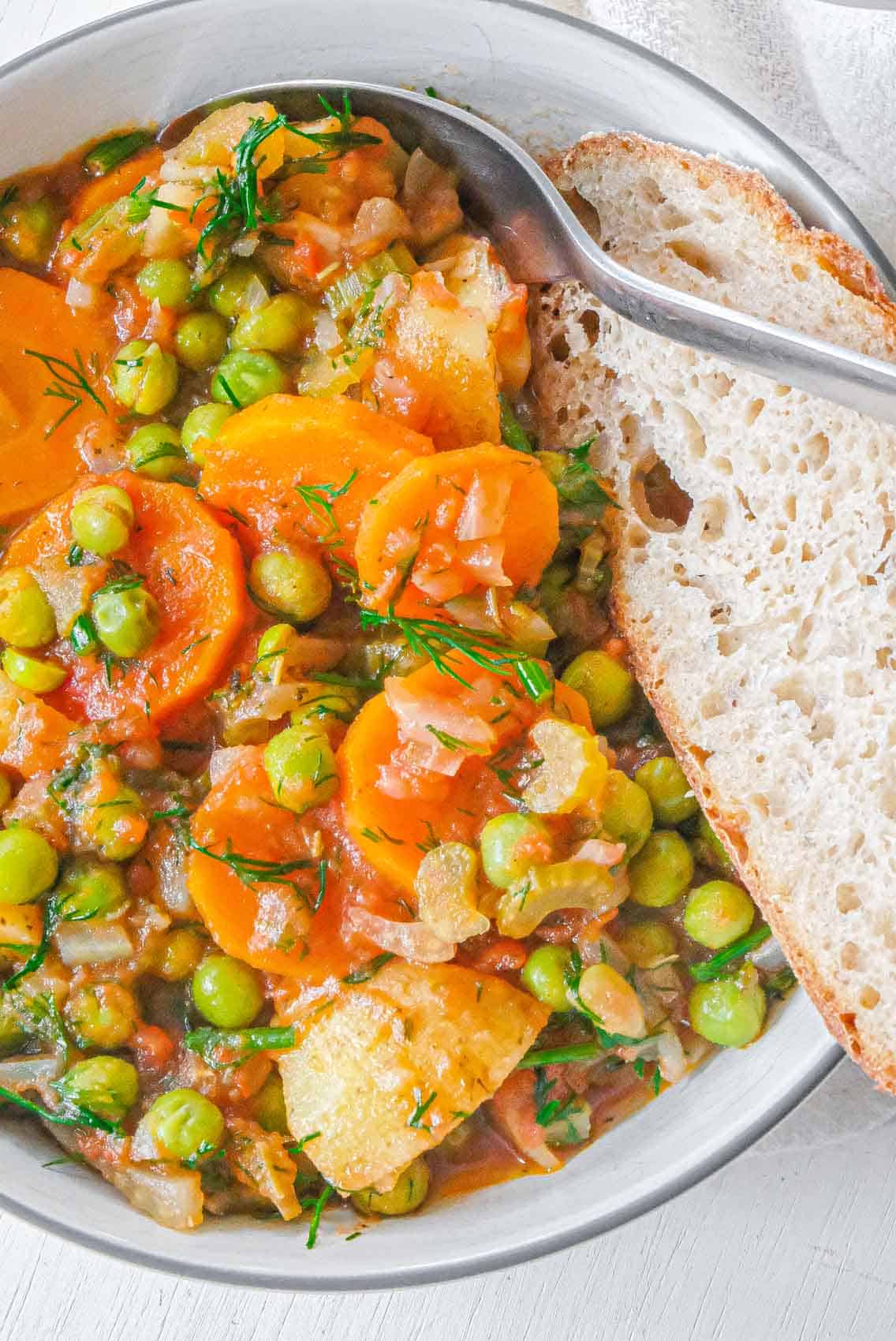 Close up of green pea stew in a bowl with bread.