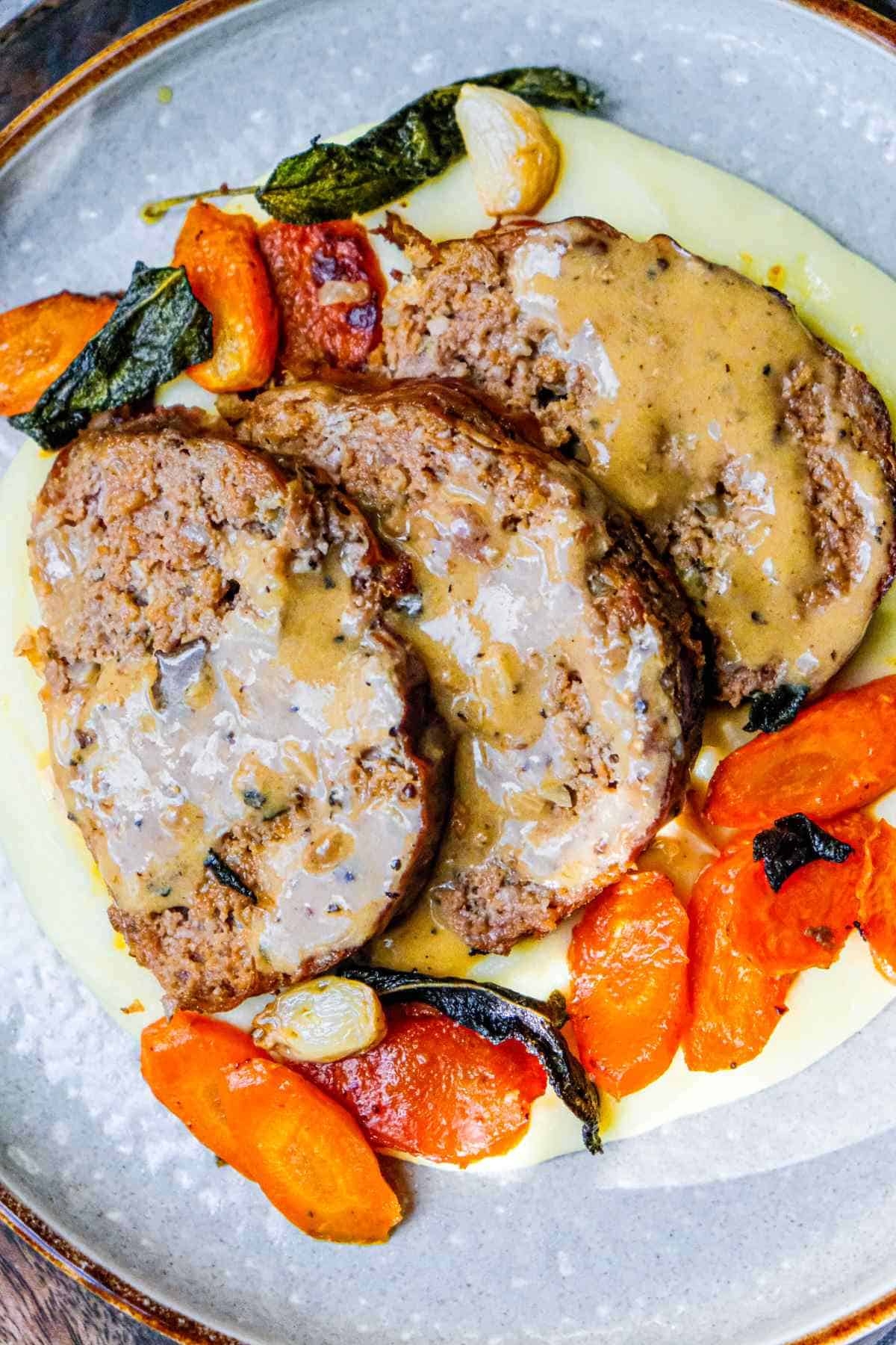 close up sliced meatloaf over mashed potatoes