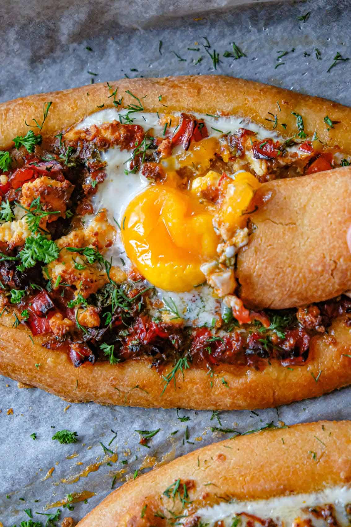 serving suggestion shakshuka bread with eggs and melted butter - piece of bread dunked into yolk