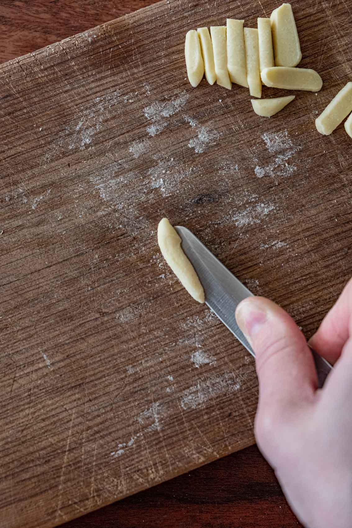 Pressing a small piece of pasta dough with a knife to make a cave shape for cavatelli or orechiette.