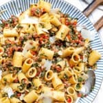 A plate of rigatoni pasta with smoked sausage, kale, red pepper and walnut crumble.