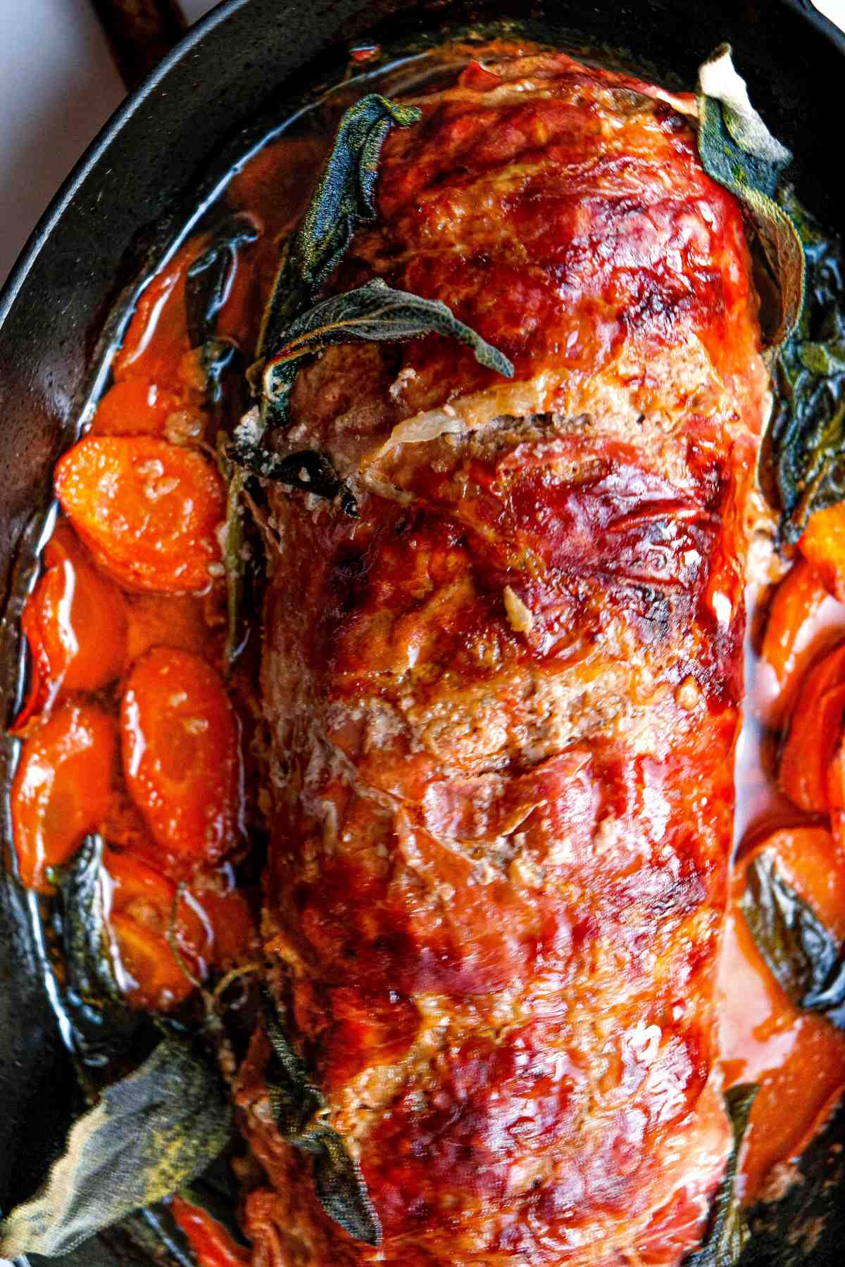 overhead view of sage and prosciutto wrapped meatloaf with carrots