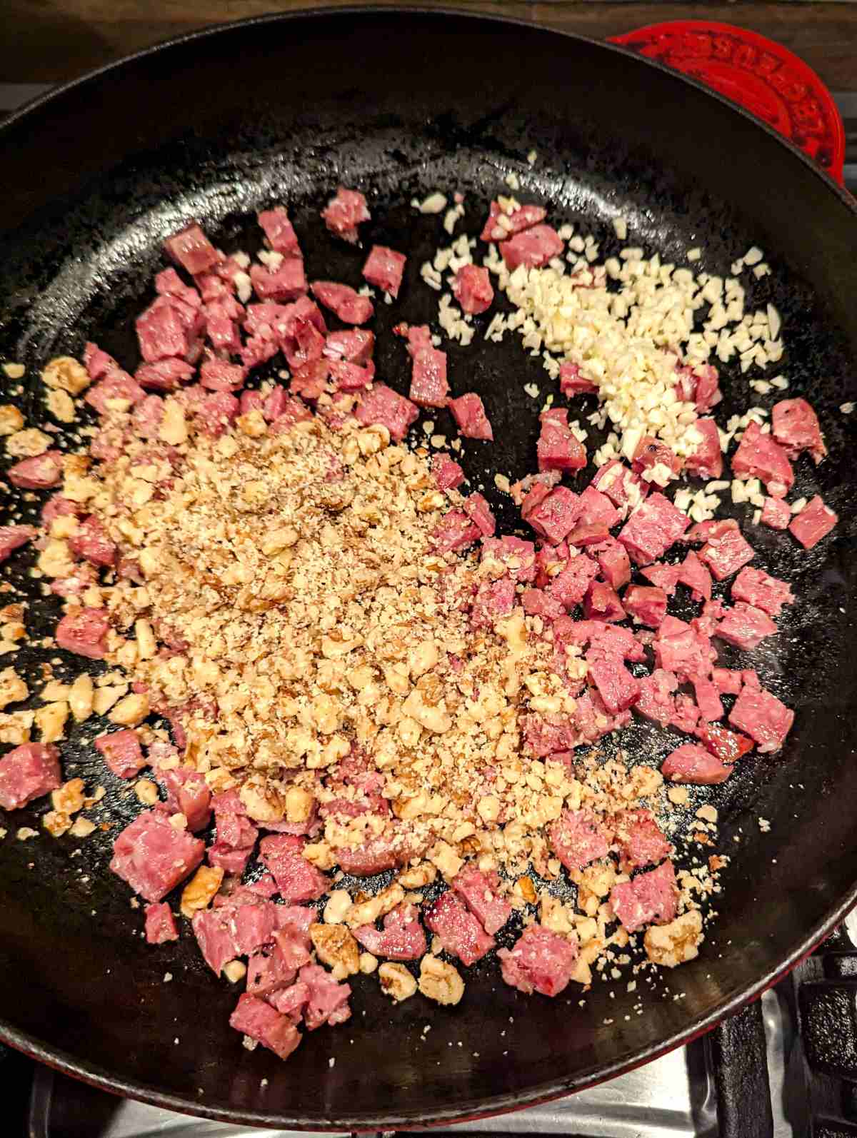 Smoked sausage, garlic and walnut sautéing in a pan.