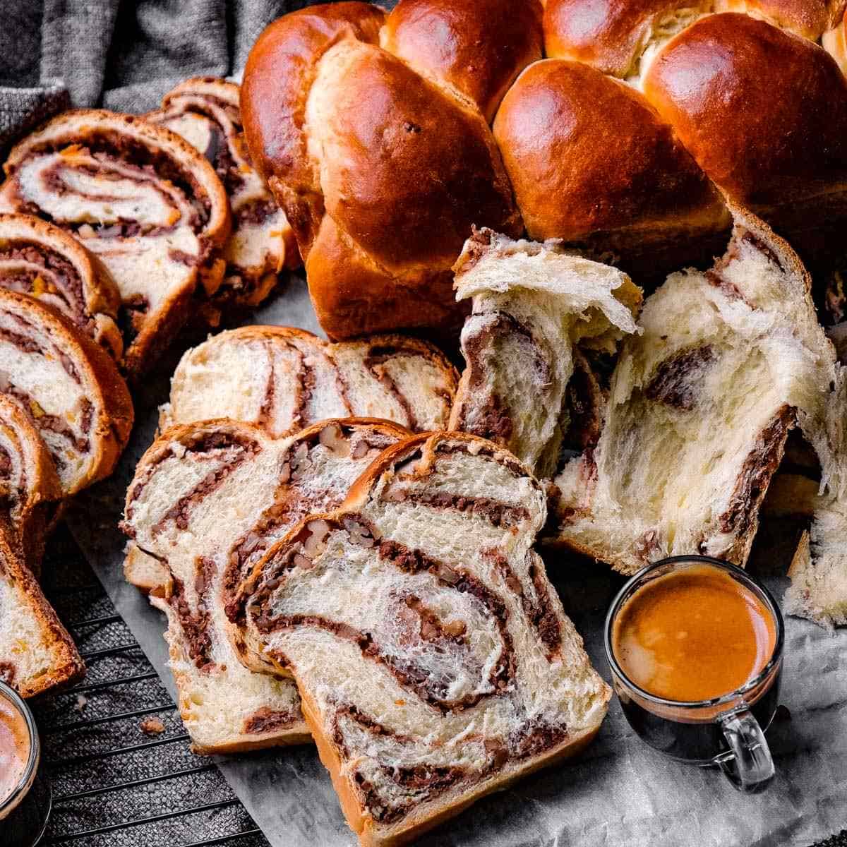 close up of a loaf of cozonac behind a few slices with a cup of coffee