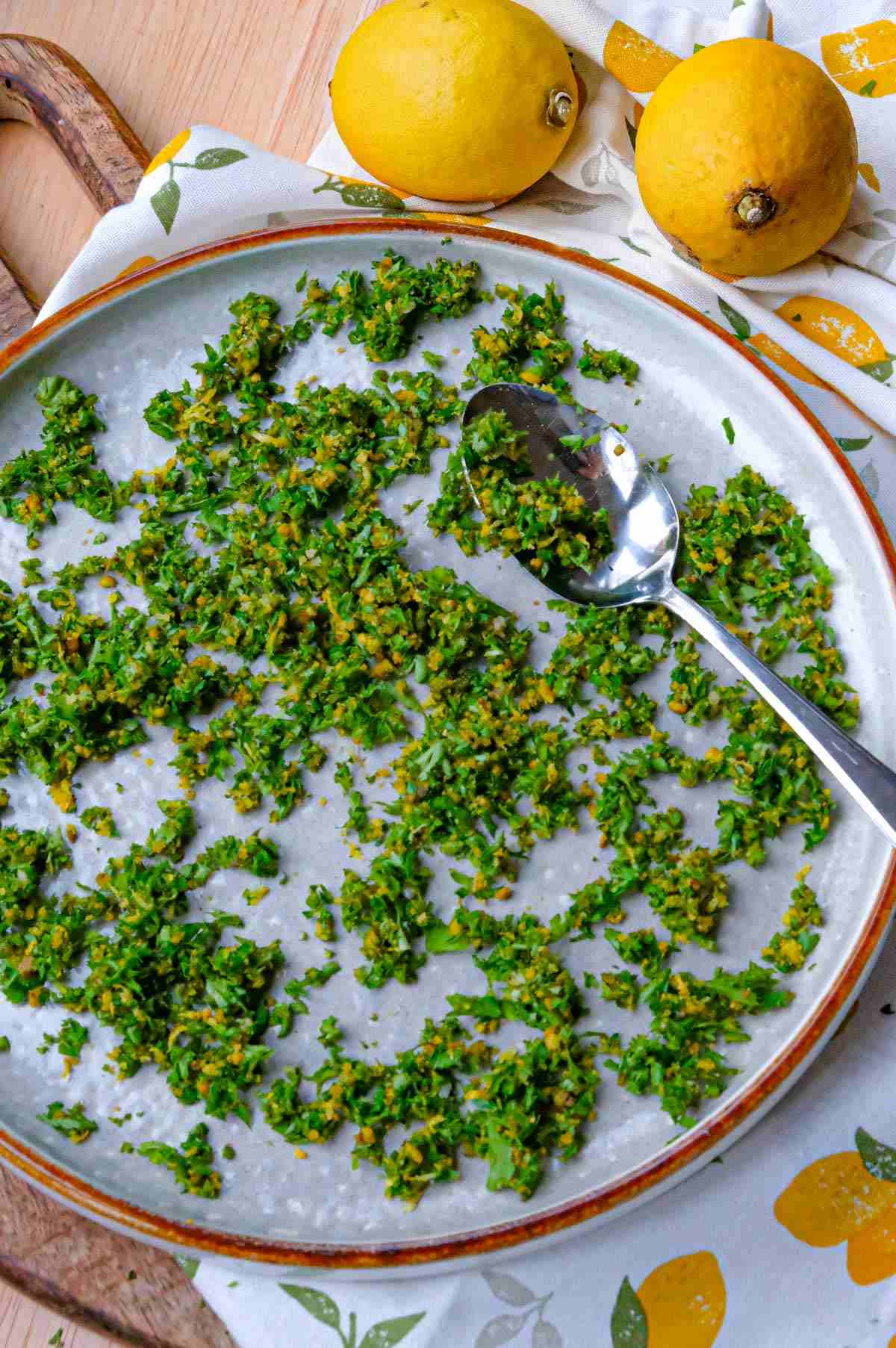 A plate full of pistachio gremolata with lemons in the background.