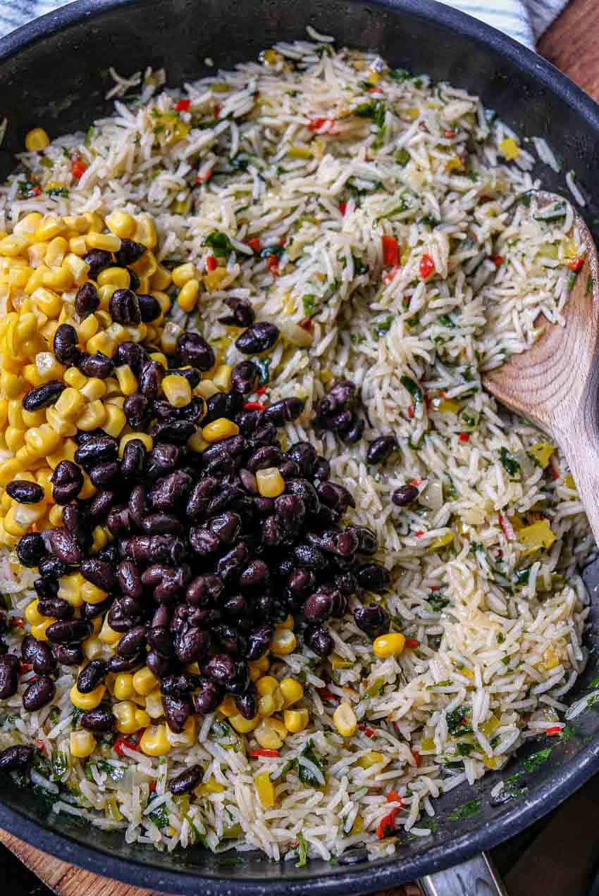 adding corn and black beans to mexican rice