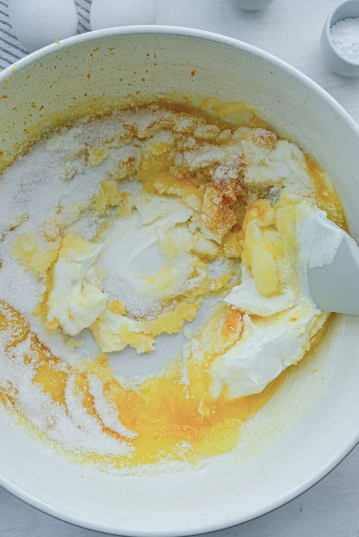 Creaming together orange zest, butter, sugar and yogurt.
