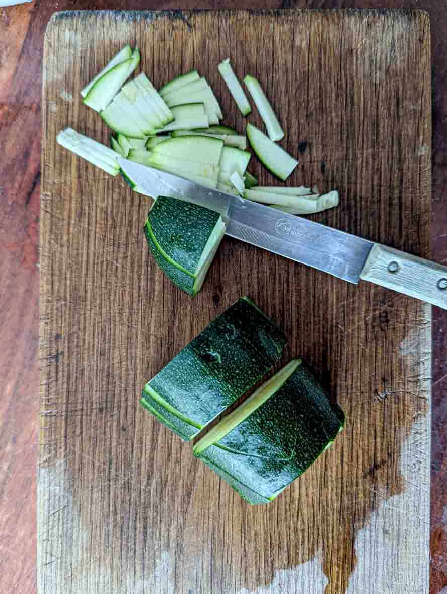 slicing zucchini into thin slivers on a cutting board