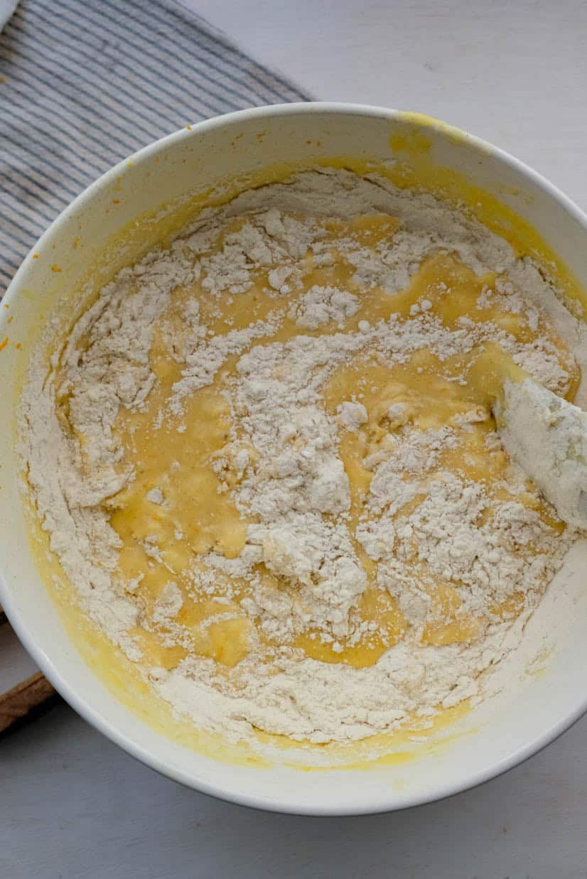 A bowl of flour with a spoon in it.