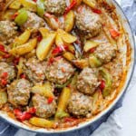 overhead view of rice meatballs with potatoes and peppers in a large pot