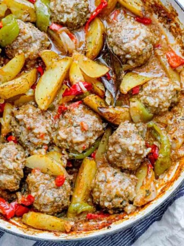 overhead view of rice meatballs with potatoes and peppers in a large pot