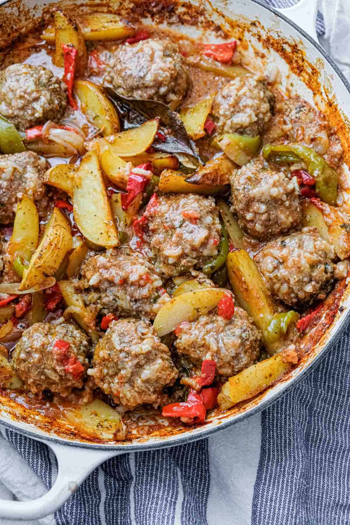 overhead view of rice meatballs with potatoes and peppers in a large pot