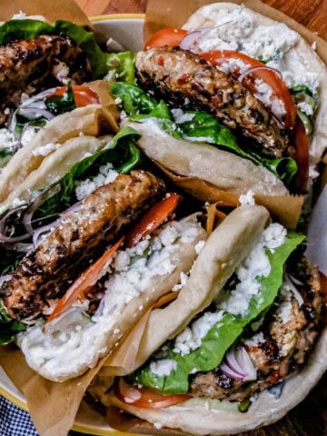 Fresh homemade Greek-style gyros with grilled meat, fresh vegetables, and feta cheese in pita bread.