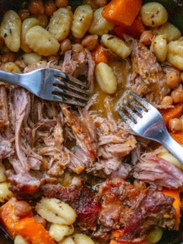 pumpkin sage pulled pork in a pot with brothy gnocchi being pulled apart with two forks