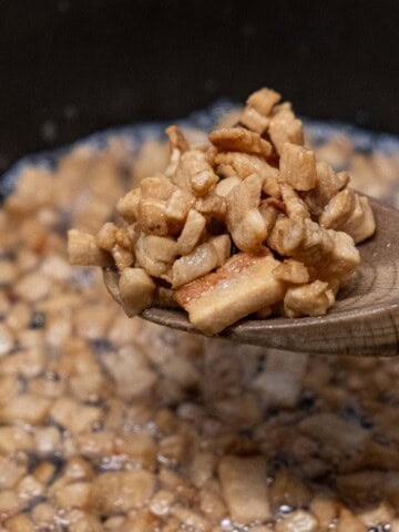 a wooden spoon holding pork cracklings