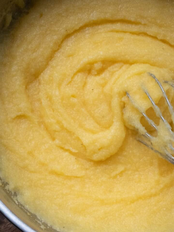 mamaliga in a pot with a whisk stirring it