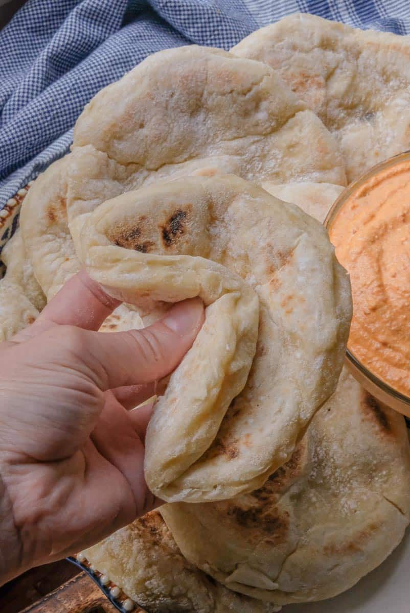 gently squeezing pita to show softness